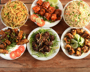 Assorted indian food on wooden background. Veg ball manchurian,chilli paneer,paneer manchurian,hakka noodles, vegfried rice and baby corn manchurian.. Dishes and appetizers of indian cuisine