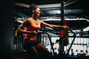 Fototapeta na wymiar Fitness female using air bike for cardio workout at crossfit gym.