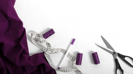 Purple sewing accessories and purple textile for needle work. Purple spools of threads, marker,...