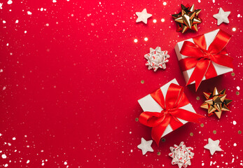 Merry Christmas and Happy Holidays greeting card background with copyspace on the left. Christmas gifts and decor on red background top view. Winter xmas holiday theme in flat lay