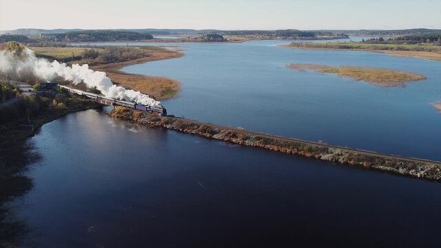 A steam locomotive passes over the bridge. Aerial view, sunny day