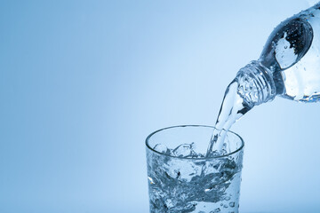 Pouring drinking water from plastic bottle into glass