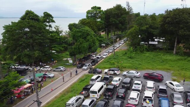 AERIAL: Drone travels Above the Packed Parking Zone with Cars to the Busy Road, People Wait in Queue to be Transported by Ferry from The Koh Chang Island to Mainland of Trat, Thailand, Asia.