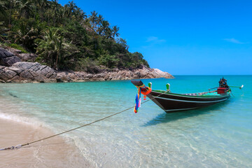 Fototapeta na wymiar Long tail boat moored at beach in turquoise water in Koh Phangan, Thailand, Asia