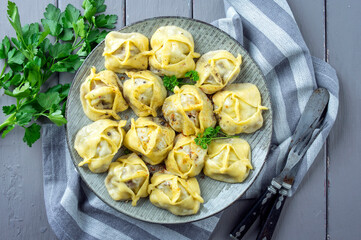 Traditional steamed Russian pelmeni with red pepper offered as top view on a rustic design plate