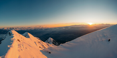 Winter panoramic view of gorgeous pink sunrise over glacier and high mountain peaks in the Alps....