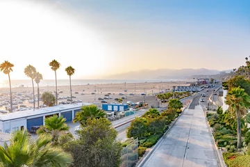 Gardinen Scenic California coast view of beach, palm trees, mountains and highway. Miles of summer weather coastal city landscape. Vehicles drive in traffic, other cars parked on sand at Santa Monica Pier. © Debbie Ann Powell