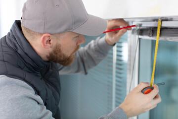 young man installing window shades at home