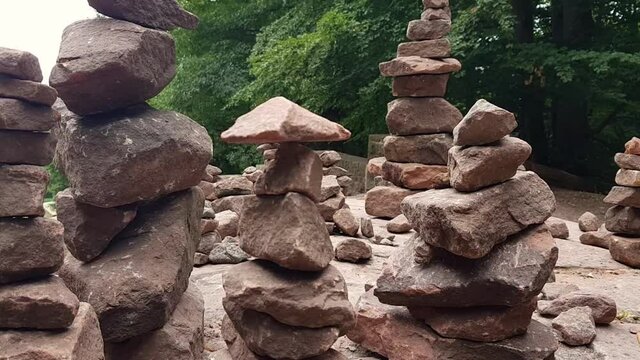 Close up zoom out of small rock balancing on top of stacked rocks on table.