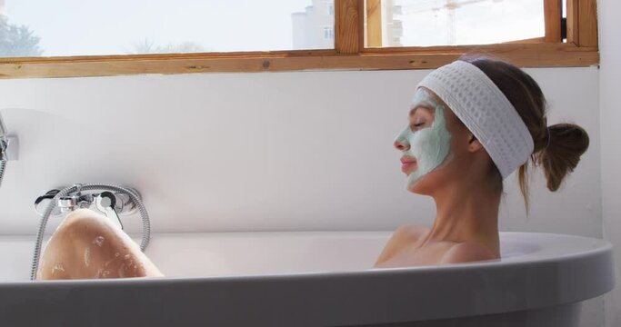Woman wearing face pack relaxing in bathtub