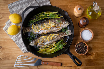 grilled trout with lemon and herb on iron skillet pan