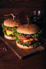 Two home made fresh tasty burgers with lettuce and cheese on wooden table.