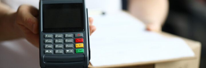 Obraz premium Close-up of delivery service and male holding cashier machine for fast payment. Nfc technology counter. Person with clipboard for sign. Client make transaction pay bill on terminal