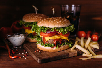 Two home made fresh tasty burgers with lettuce and cheese on wooden table.
