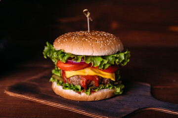 Home made fresh tasty burger with lettuce and cheese on wooden rustic table.