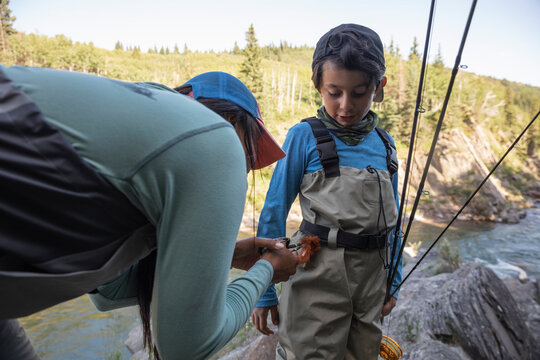 Mother helping son wearing fishing waders
