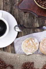 A white cup of coffee and cake on a wooden background. Coffee beens and coffee grinder on a linen fabric.