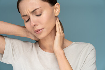 Woman suffering from chronic neck pain, gently massages with hands, feeling tired after long hours work in incorrect posture, closed eyes. Exhausted female having upper back ache, muscle strain. 