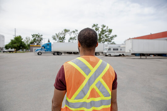 Rearview of warehouse worker looking at container truck parking