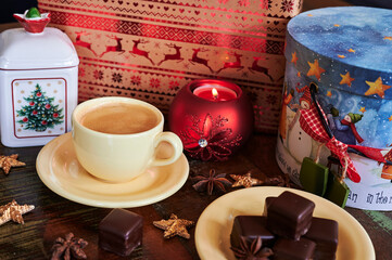 Atmospheric scene of a Christmas decorated wooden table with sweet gingerbread pastry and a coffee cup.