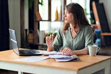 Young woman working from home office. Freelancer using laptop and the Internet. Workplace in living room.