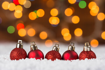 Christmas baubles on snow with colorful bokeh lights