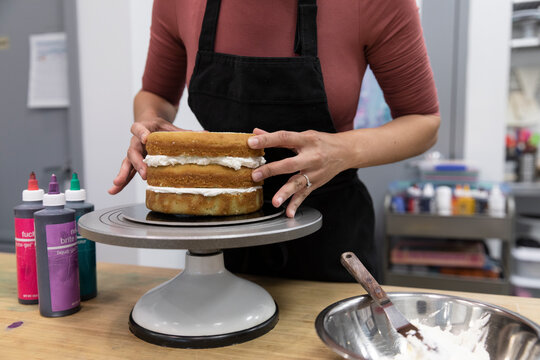Mid adult woman placing top layer on handmade cake
