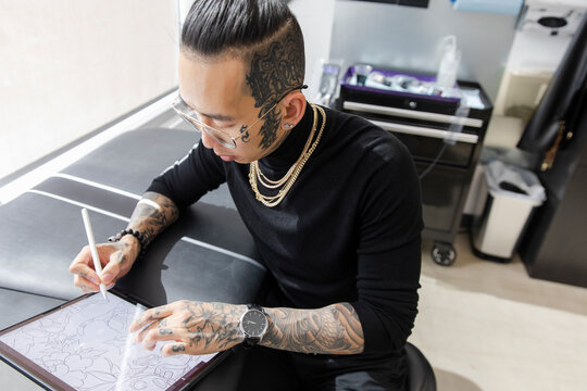 Tattoo artist designing on tablet in studio