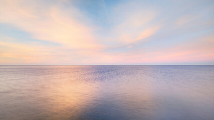 Baltic sea under the colorful sunset sky. Stunning seascape. Golden sunset light through the pink...