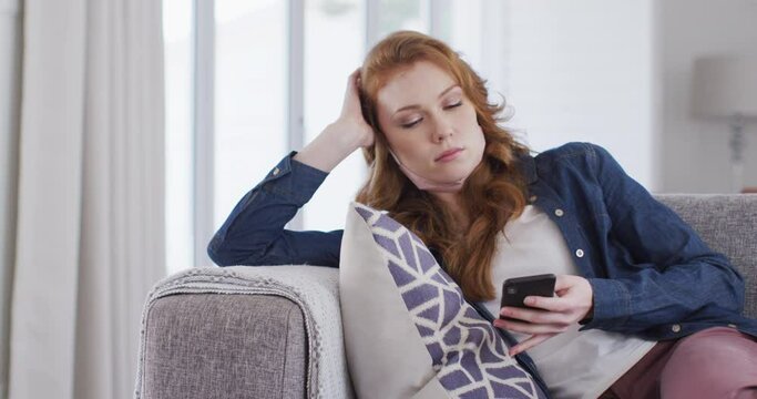 Woman using smartphone while sitting on couch at home