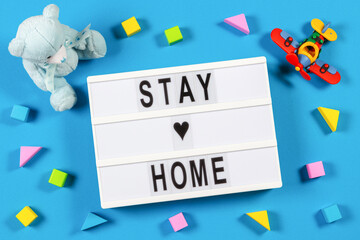 Stay at home. Lightbox with text STAY HOME and baby kid toys on blue background. Coronavirus, Covid-19, quarantine and social distancing concept
