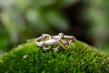 Sterling silver ring in the shape of lizzard on green moss background