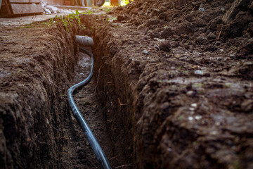 Water and sewer pipes in a digged trench deep in the ground. Sewerage and water system repair concept.