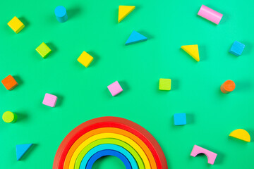 Baby kids toy background. Wooden stacking rainbow and colorful blocks on light green background. Top view