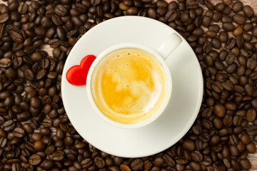 Cup of espresso coffee with scattered coffee beans, decorative red fabric heart and with space for text. Poster.