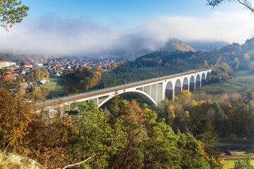 Fototapeta premium Railway bridge in autumn in the Czech Republic of the village Dolni Loucky. Train transport. Autumn foggy morning in the countryside.