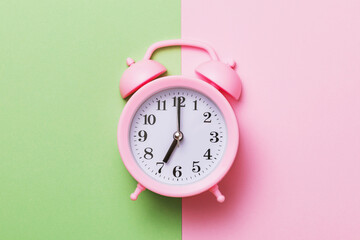 Pink alarm clock on a colored background, top view