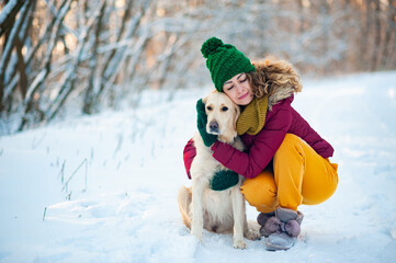 Smiling woman hugging her pet dog golden retriever near face. Golden retriever playing with a woman walking outdoors winter day, warm clothing. love and care for the pet.