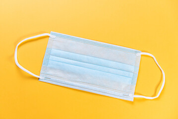 blue disposable medical mask isolated on yellow background