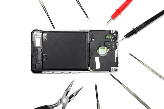 Disassembled old Smartphone, tools: screwdrivers, probes, pliers top view.