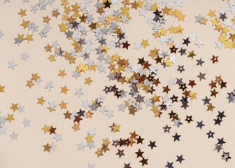 Gold stars glitter on nude background. Festive holiday pastel background.