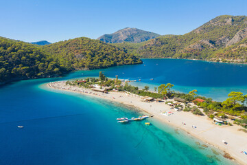 long sand beach in emerald lagoon and green mountains with blue sky and copy space