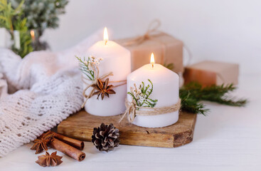 Obraz na płótnie Canvas Christmas candles and fir branches on a white wooden background with lights
