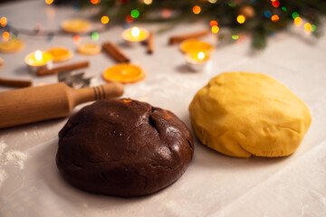 Two kneaded heaps of dough on the white table, chocolate and yellow shortbread. Christmas baking, preparation for winter holidays.