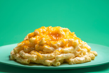 Mac and cheese portion on a green background. Macaroni with cheese on a plate.
