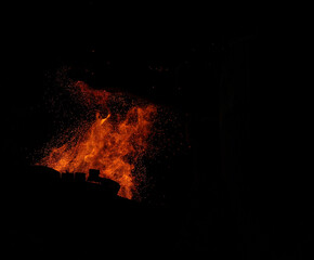 fire flames with sparks on a black background. In the foreground, the iron hammer silhouette is visible.