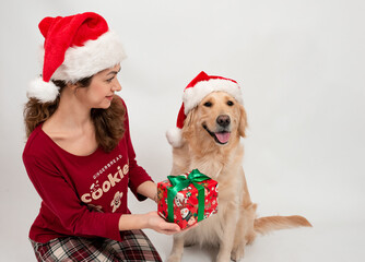 Curly girl in Santa Claus hat with dog labrador retriever waiting for the New Year. Celebrating Christmas or New Year eve, pajama party.