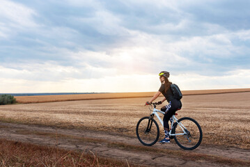 Fototapeta na wymiar girl on a bicycle travels on a sunny field