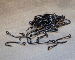 Black fishing hooks lined up to form a path at the beginning, dispersed and at the bottom more complex and compact. Hooks used for fishing of several species, including tilapia and catfish.