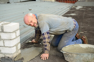 Senior man is on all fours repairing roof.